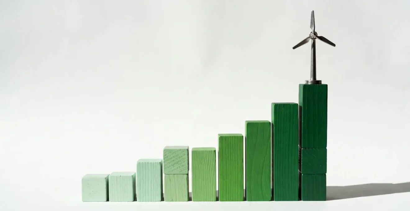 Graphique à barres en bois avec une éolienne sur la barre la plus haute, symbole de croissance et d'énergie verte.
